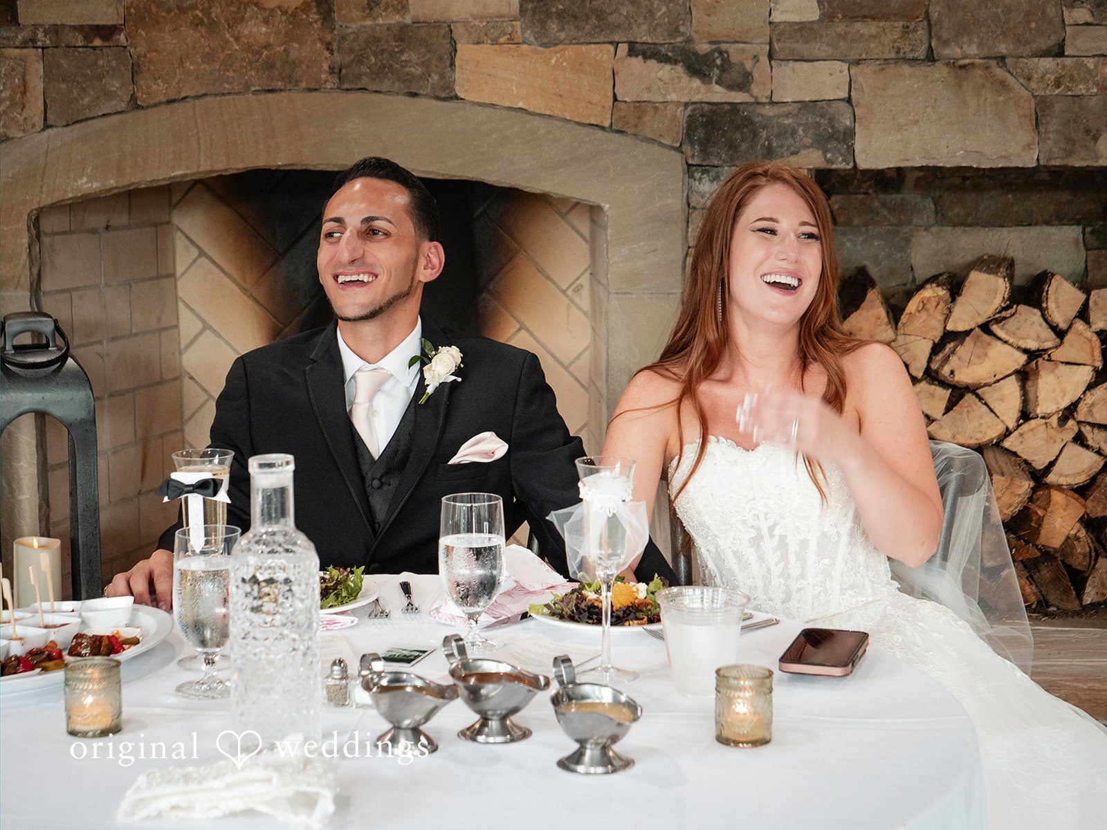 Vincenzo + Kristin A bride and groom sitting at their decorated sweetheart table during a reception.