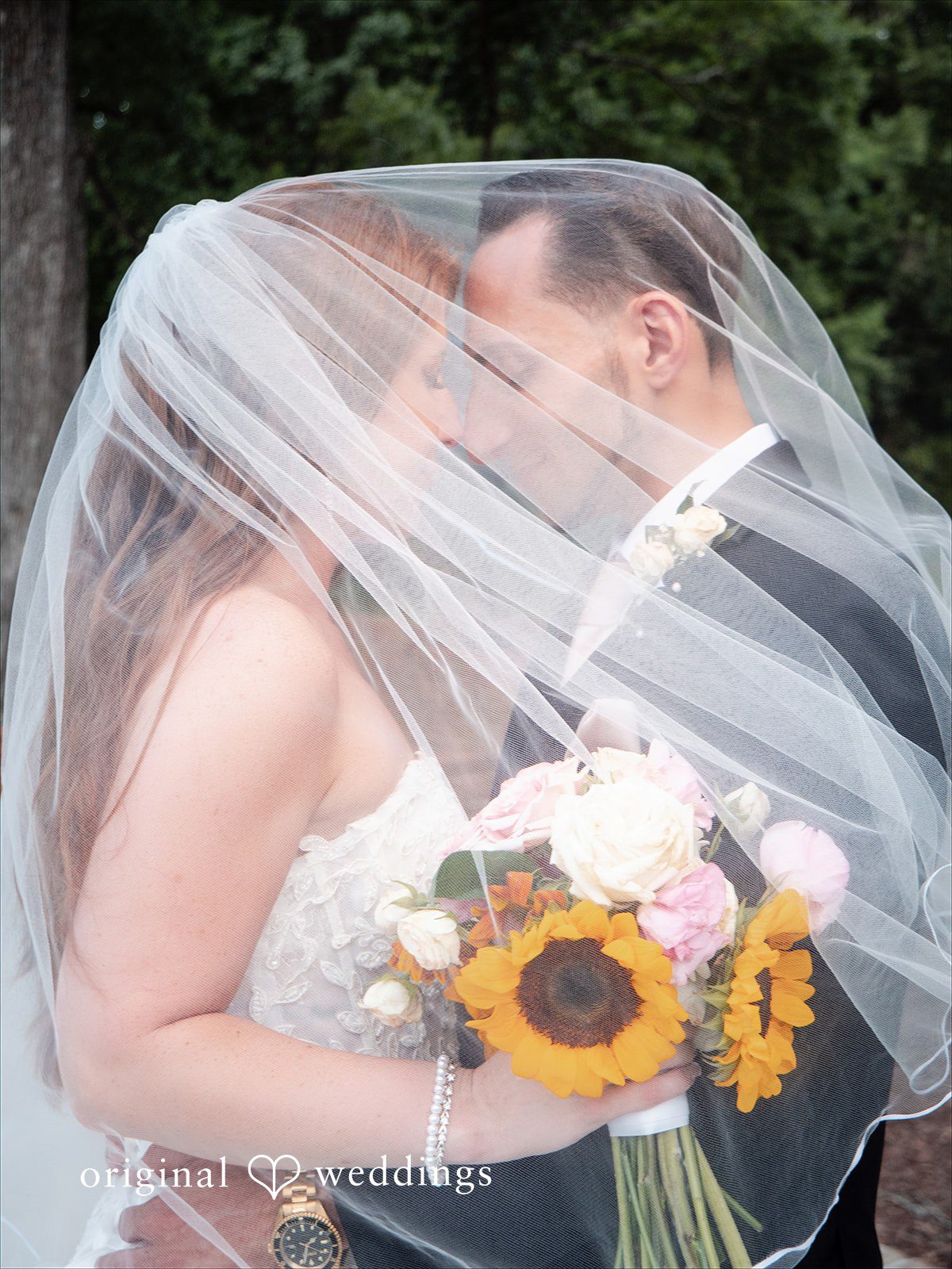 Vincenzo + Kristin A bride and groom smiling together under a long, sheer wedding veil.
