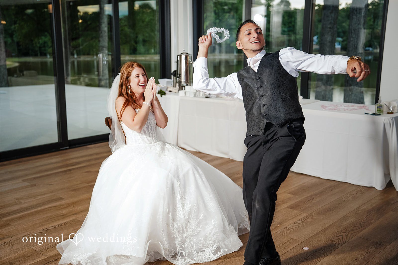 Vincenzo + Kristin A bride dancing joyfully with a groom on a wooden dance floor.