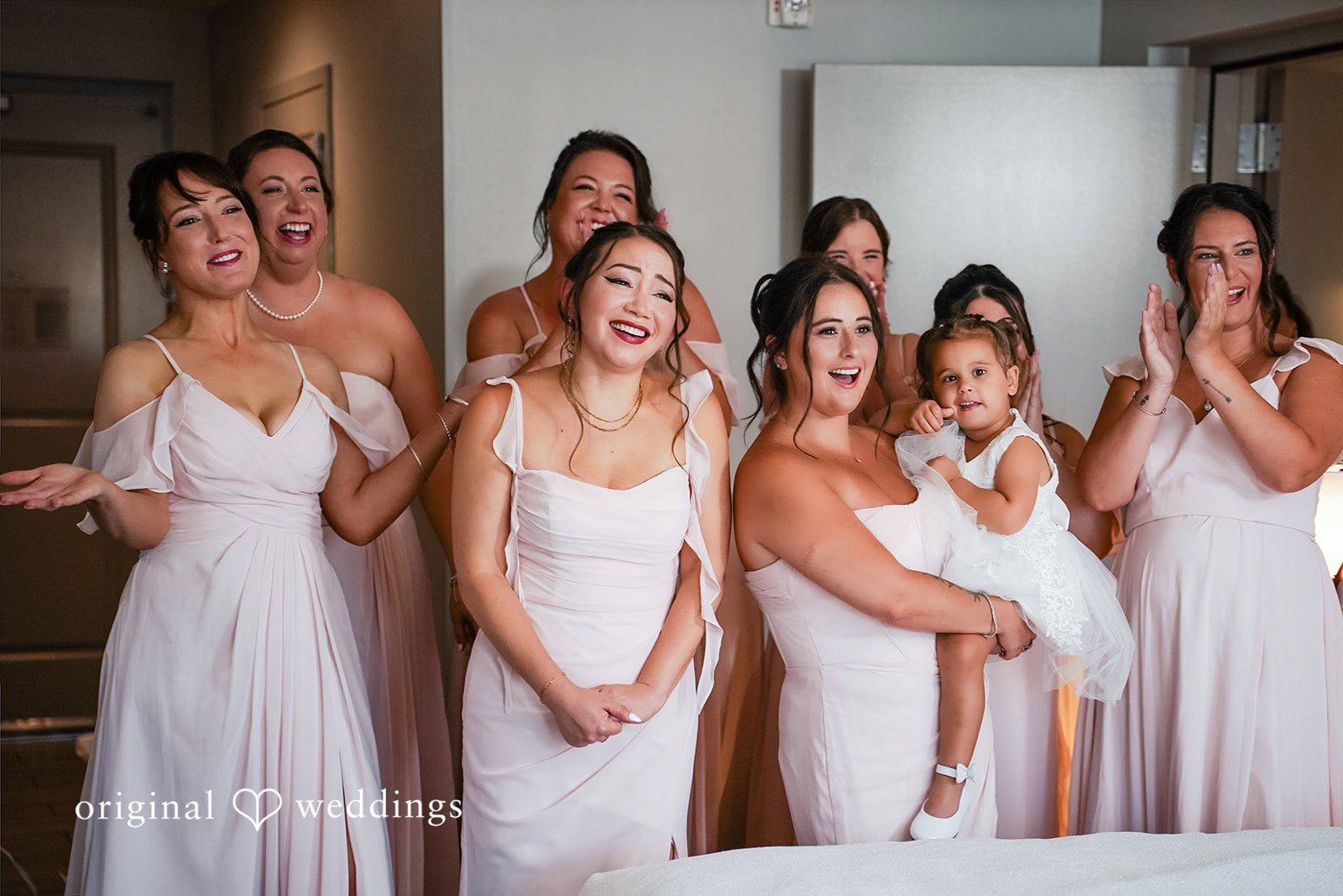 Vincenzo + Kristin Five bridesmaids wearing matching light-colored gowns standing in a row.