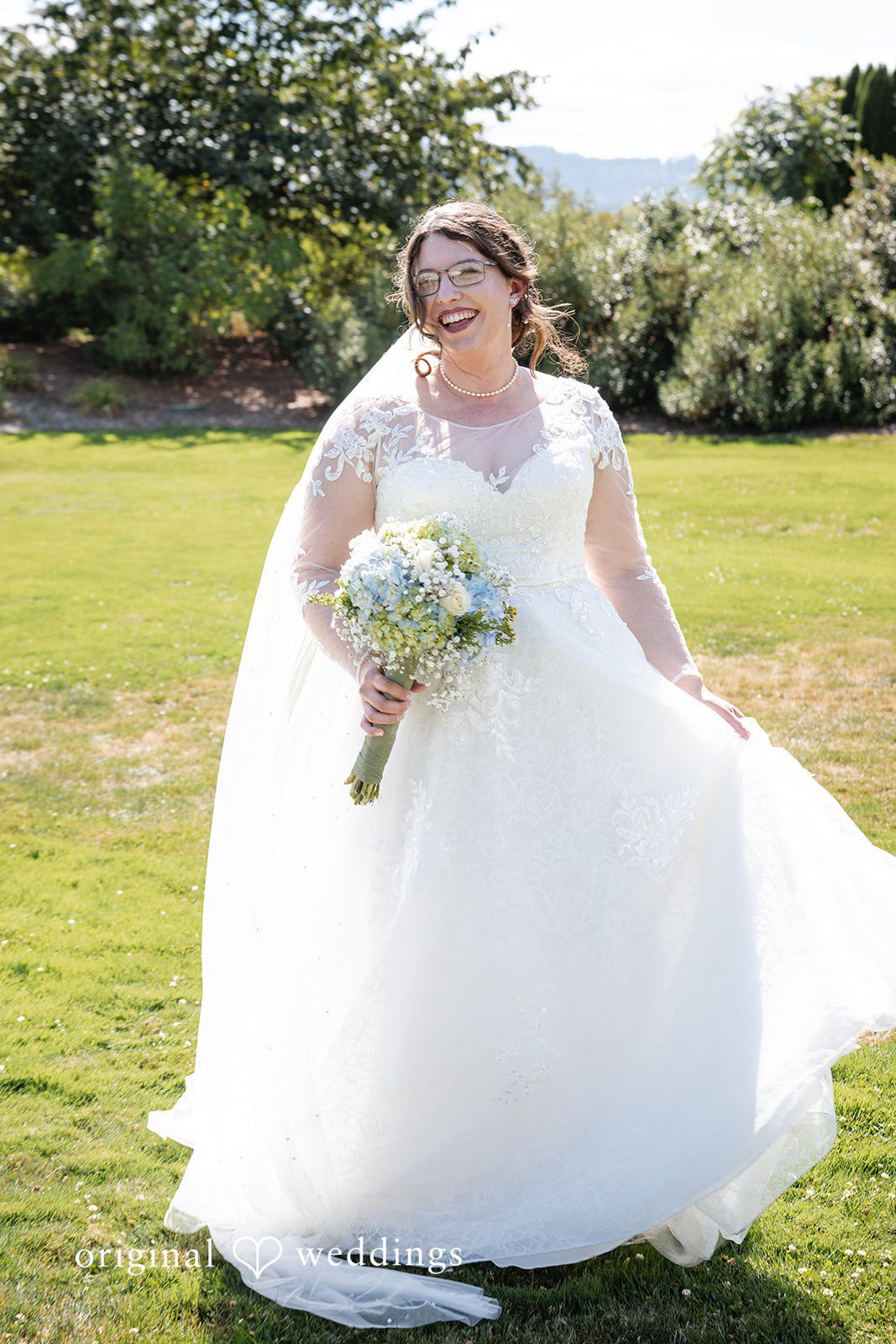 Emma + Aidan A bride walking across a grassy lawn while holding the train of her gown.