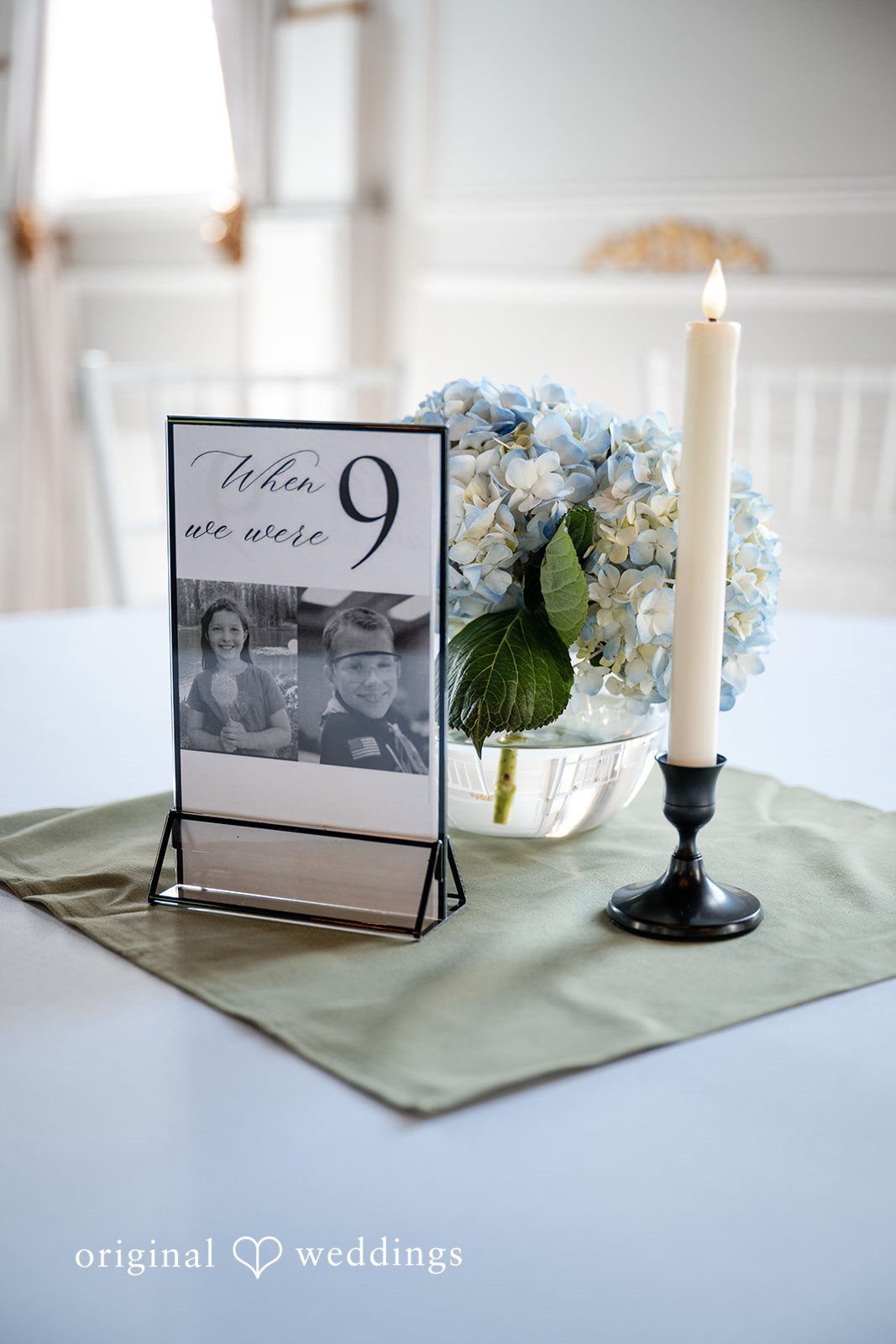 Emma + Aidan A table setting featuring a framed number nine next to a floral centerpiece.