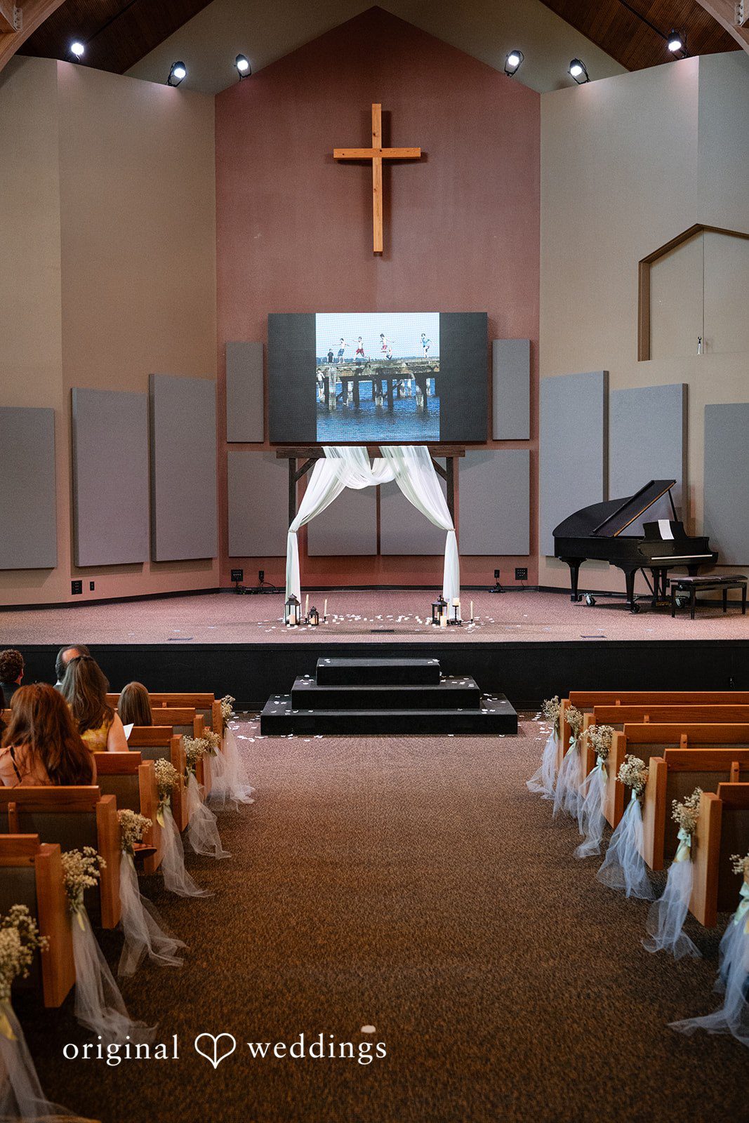 Emma + Aidan An empty church sanctuary with rows of wooden pews facing a central altar.