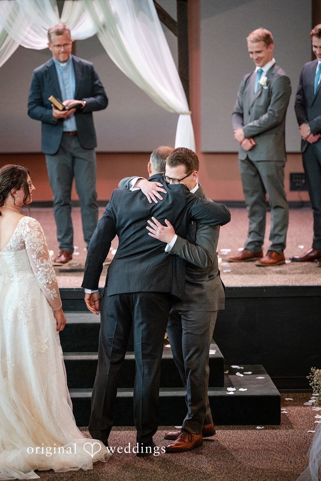 Emma + Aidan A groom hugging guests in a church aisle after the wedding ceremony.