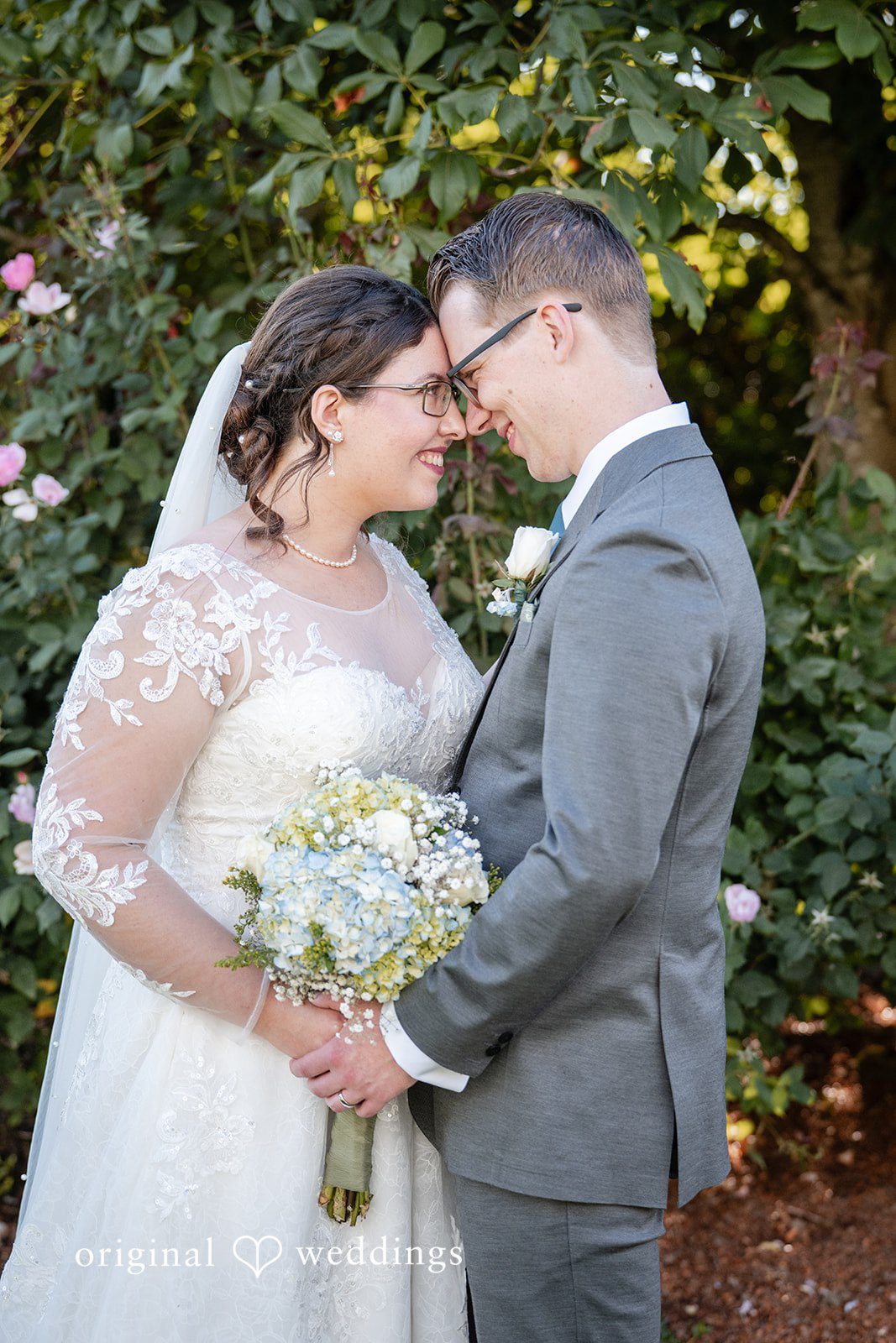 Emma + Aidan A bride and groom smiling at each other while holding a white bouquet.