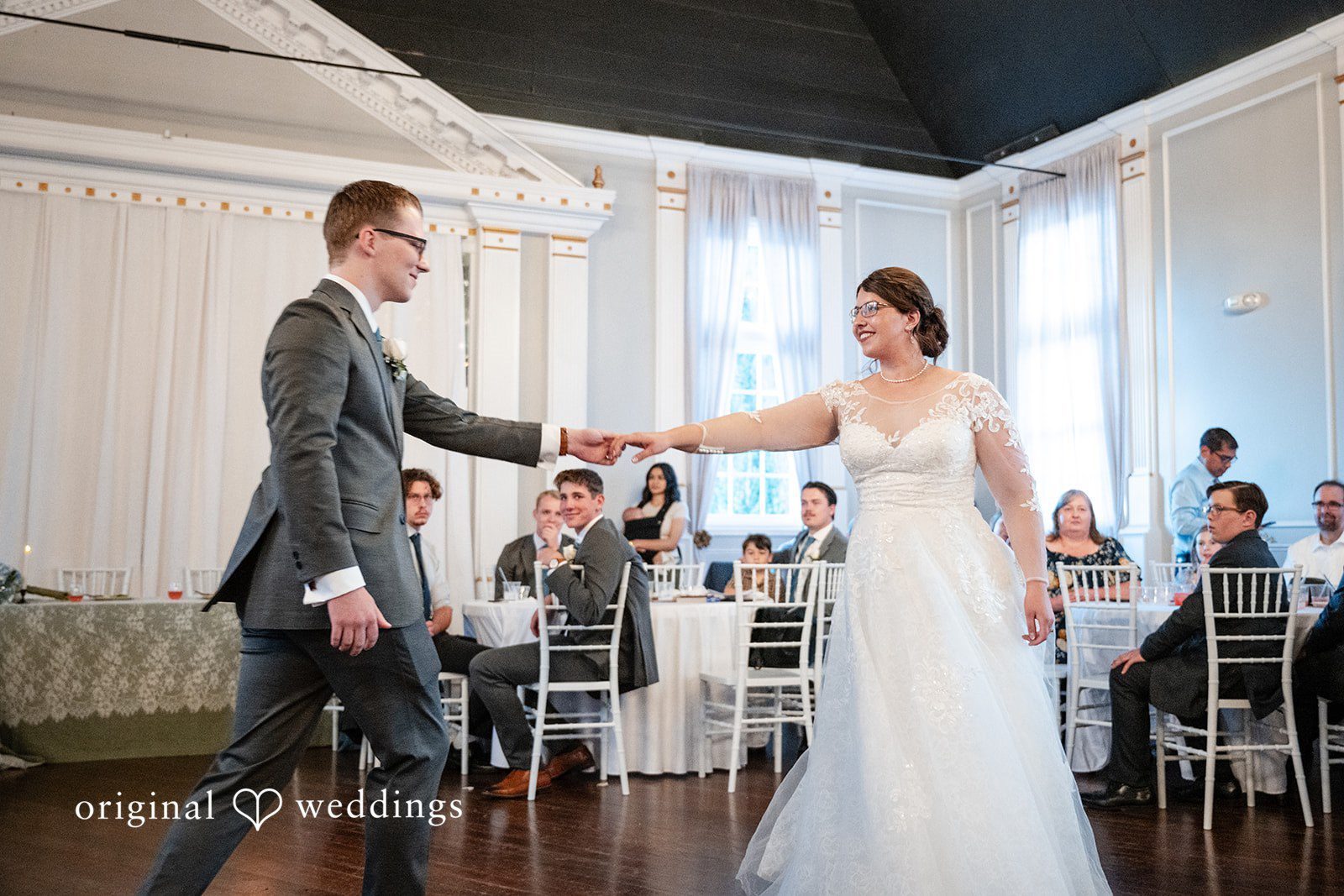 Emma + Aidan A bride and groom holding hands while facing each other on a dance floor.