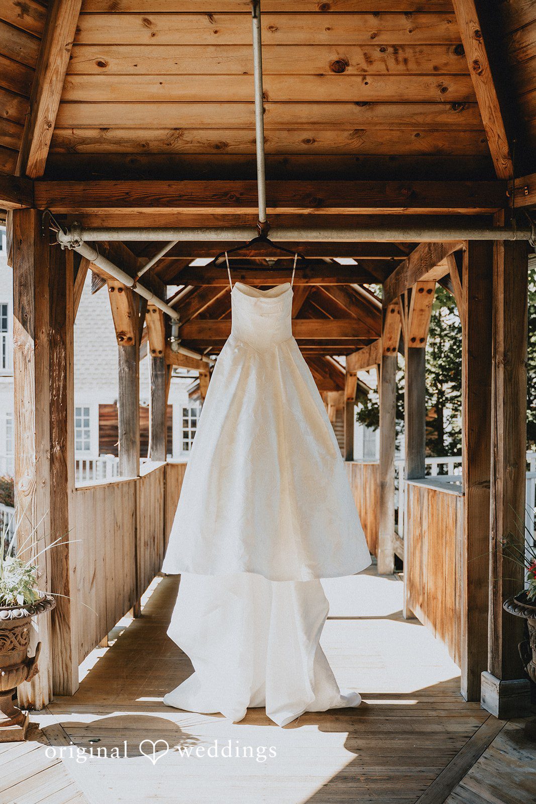 White wedding gown hanging from a wooden ceiling beam.