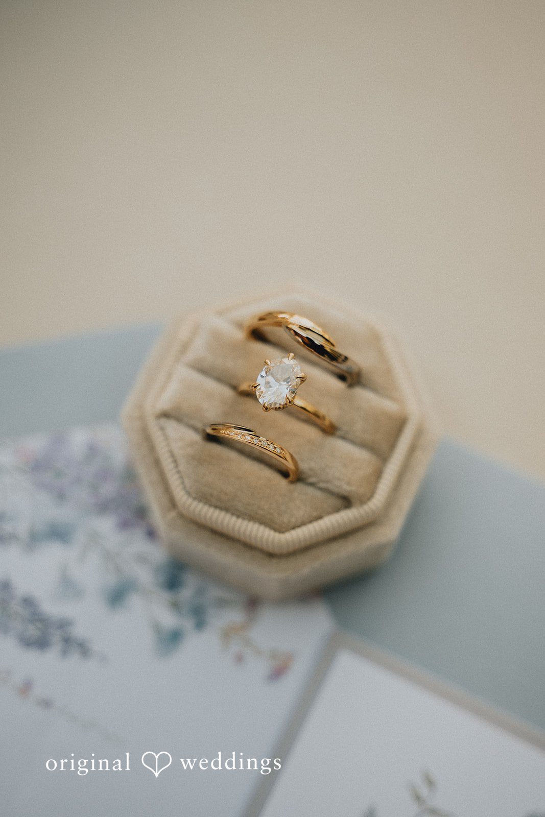 Hexagonal wooden ring box holding wedding ringd.