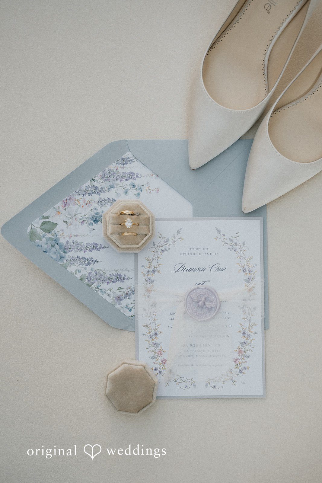 Elegant wedding invitation suite arranged next to white heels.
