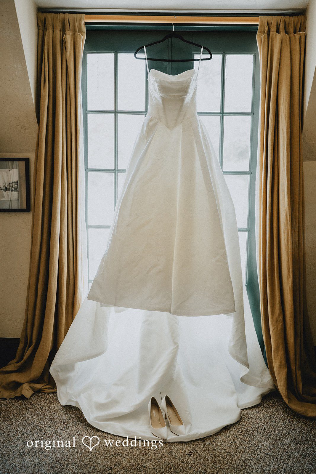 White wedding dress displayed on a mannequin near a window.