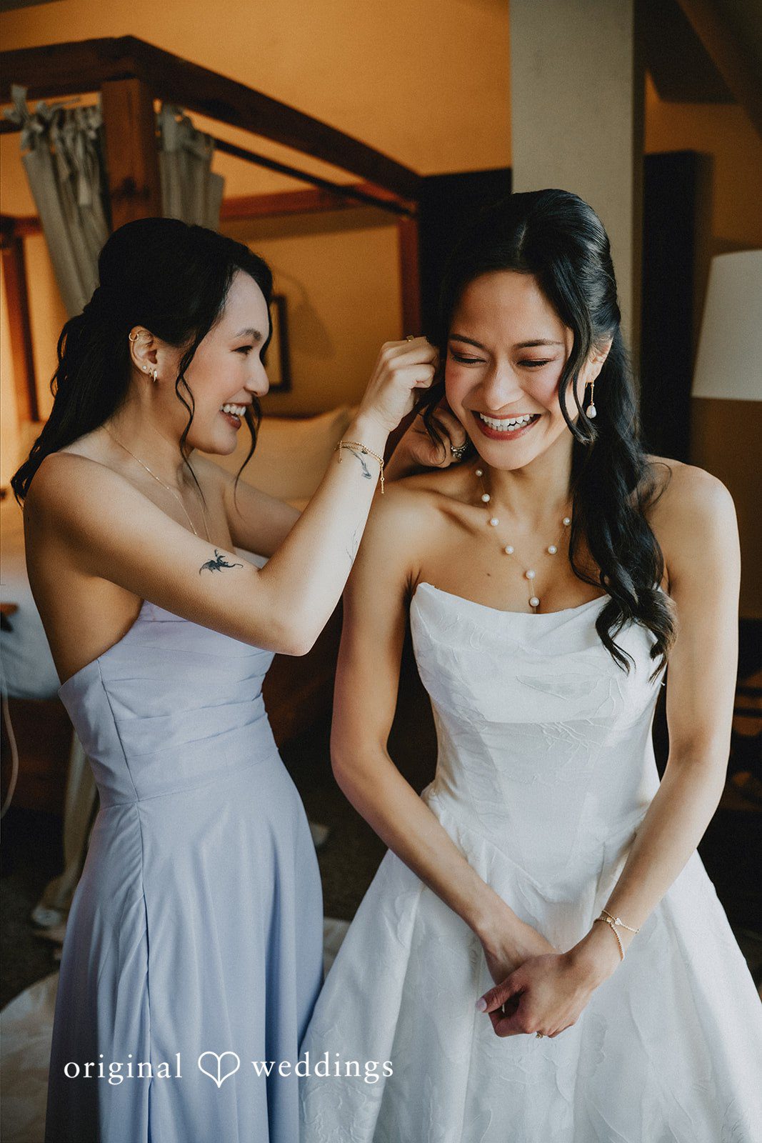 Bridesmaid adjusting the hair of a smiling bride.