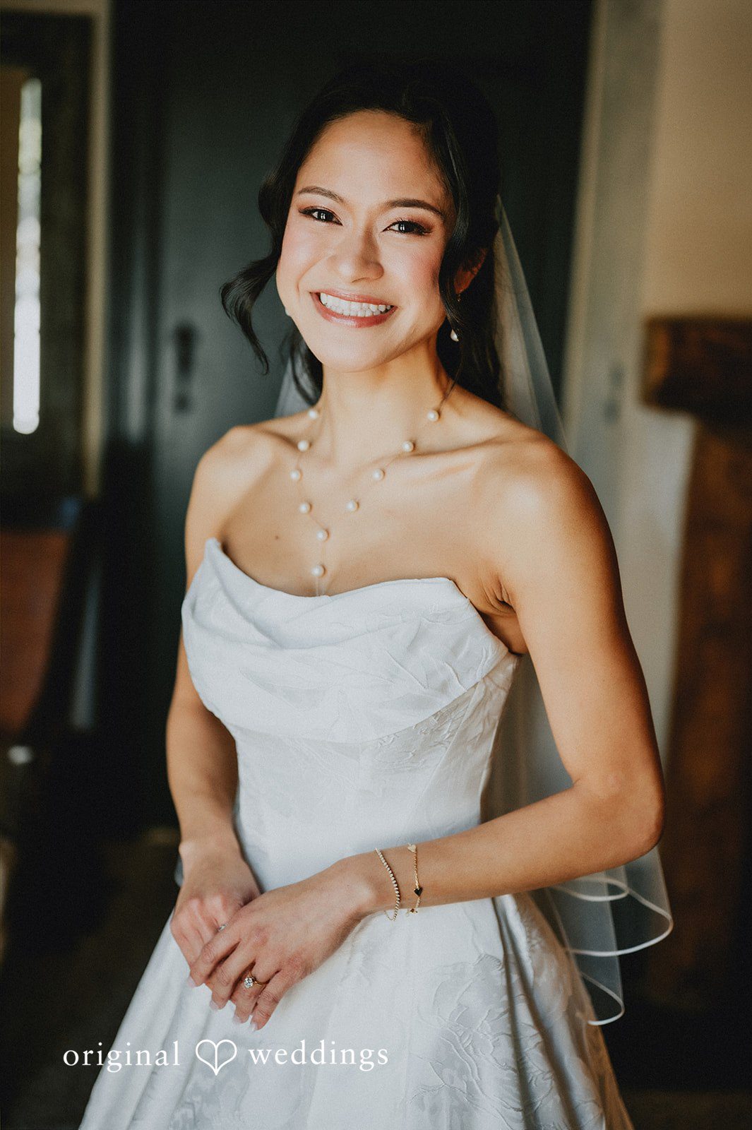 Close-up of a smiling bride in a white gown.