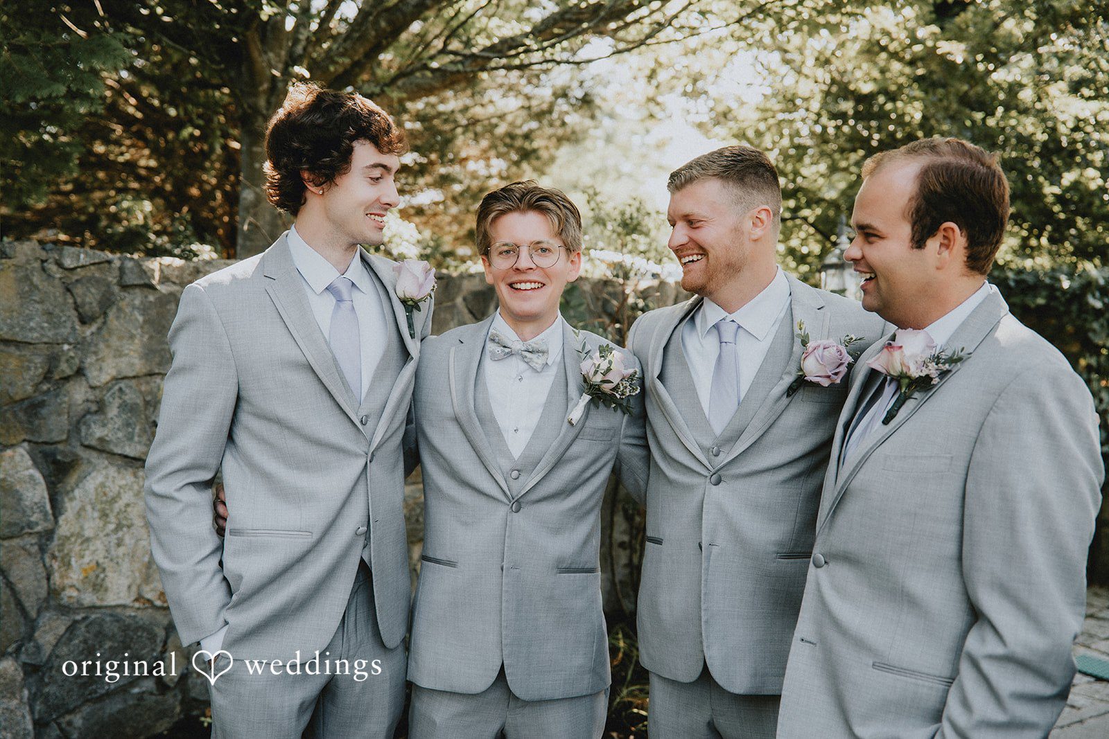 Groom and groomsmen in matching grey suits posing together.