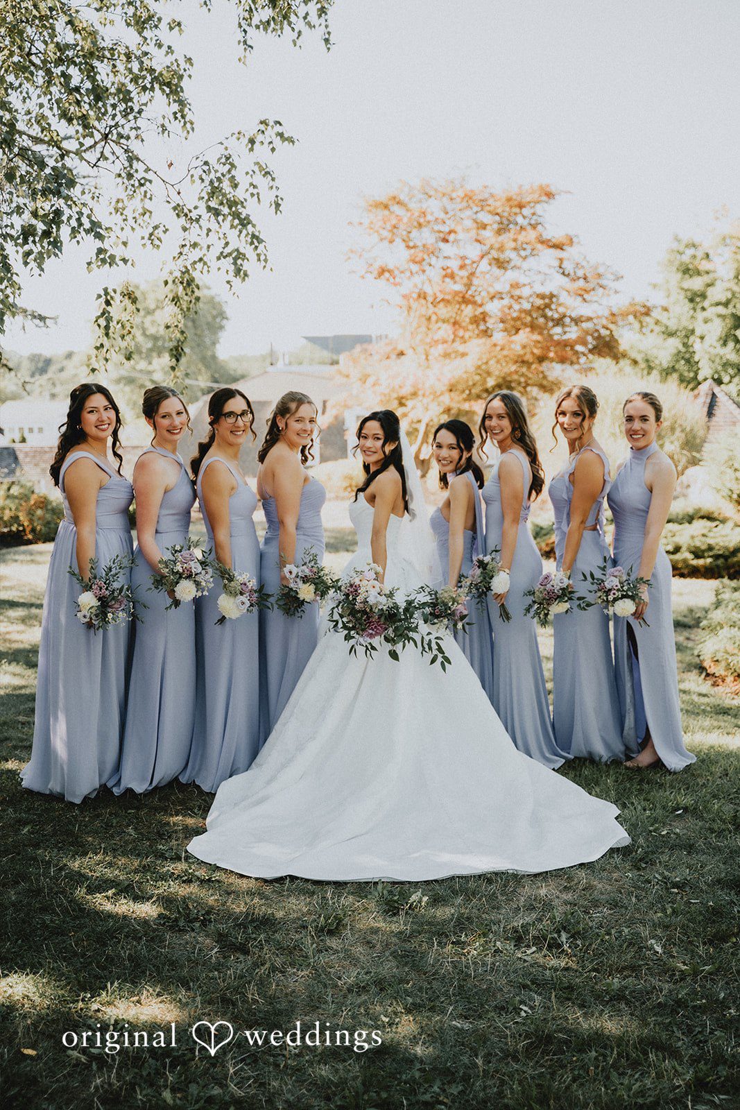 Bridal party posing together on a grassy lawn.