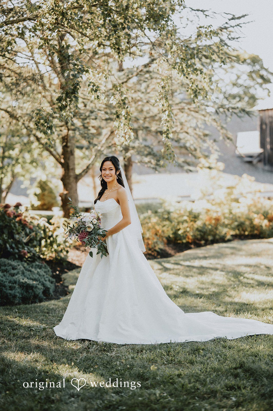 Bride posing in a long white gown on a pathway.