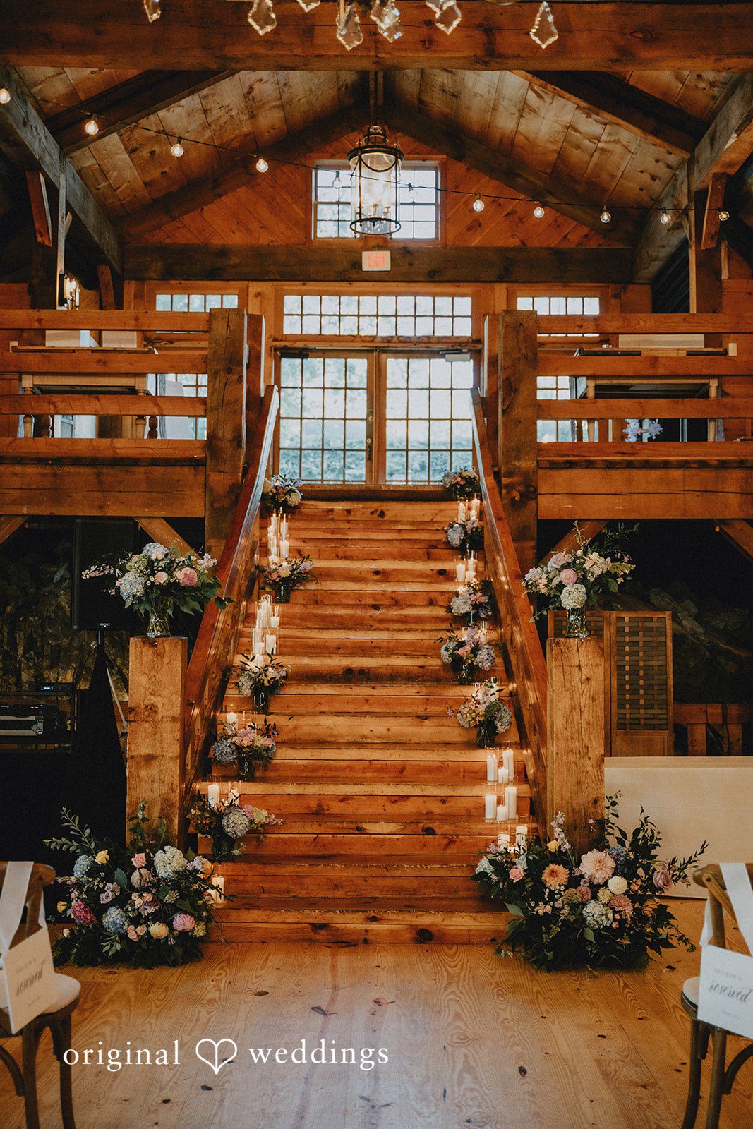 Grand wooden staircase adorned with white flower arrangements.