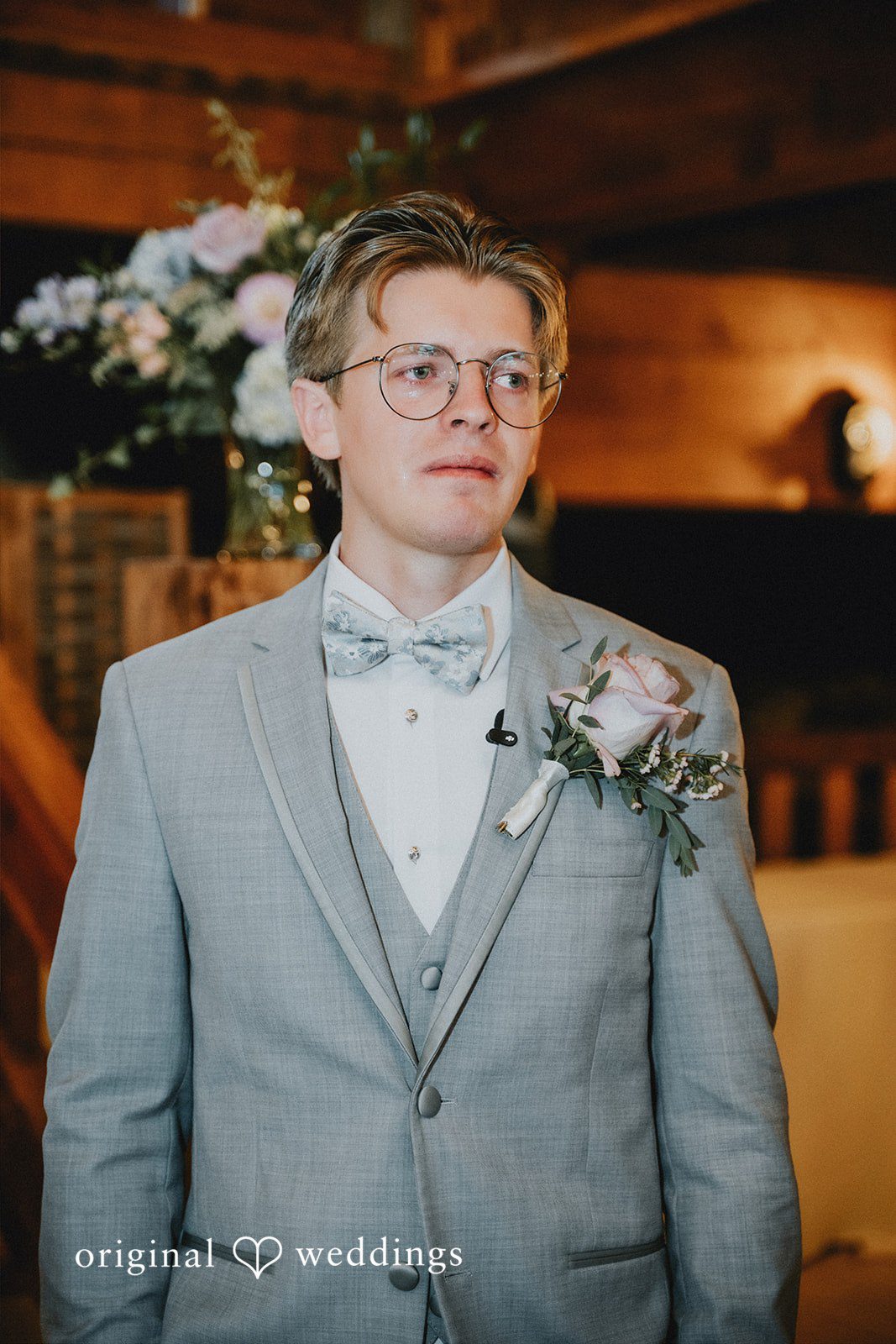 Close-up portrait of a groom wearing glasses and a bowtie.
