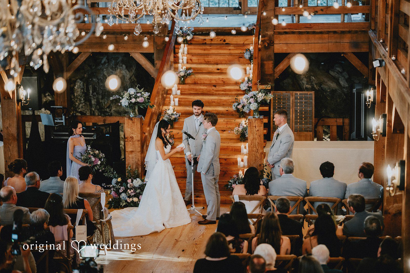 Bride and groom exchanging vows under warm, glowing string lights.