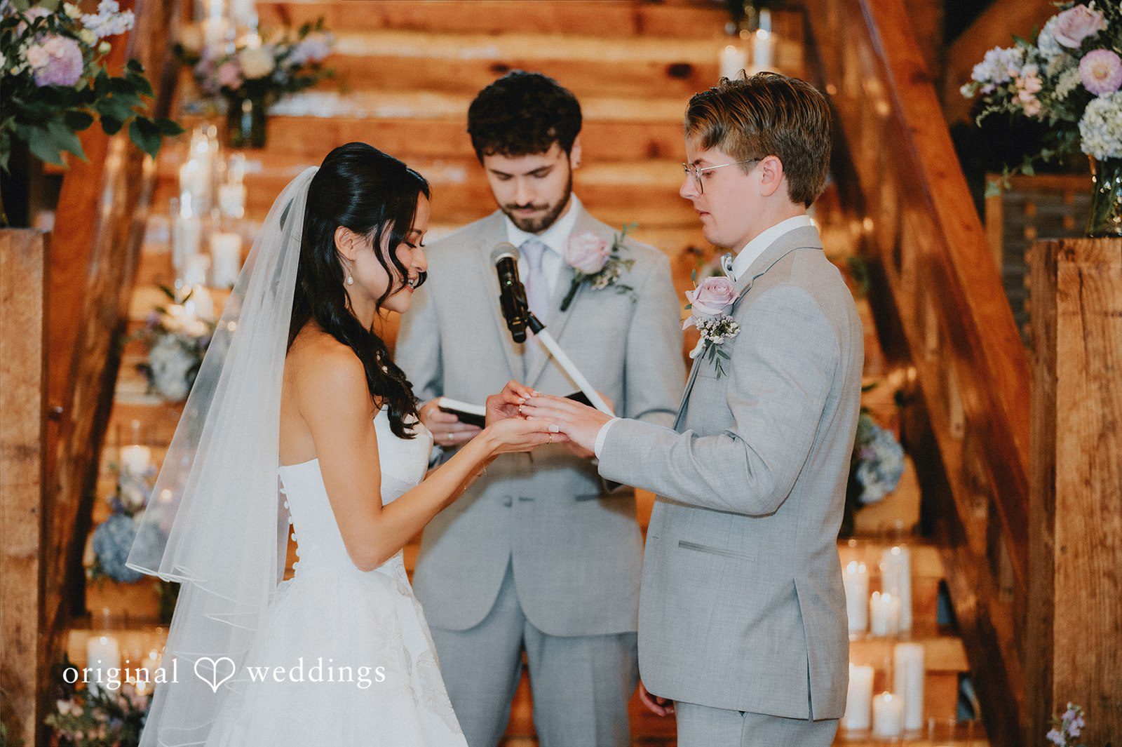 Bride placing a wedding ring on the groom's finger.