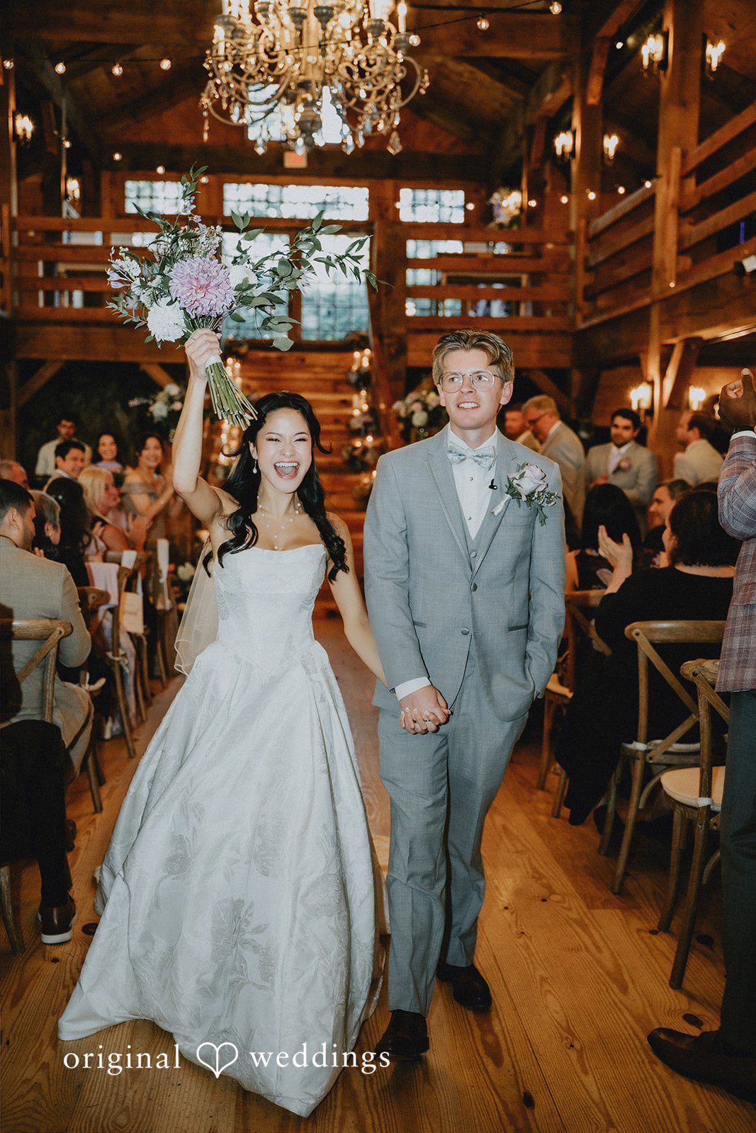 Bride in a full white gown walking down a grand staircase with the groom.