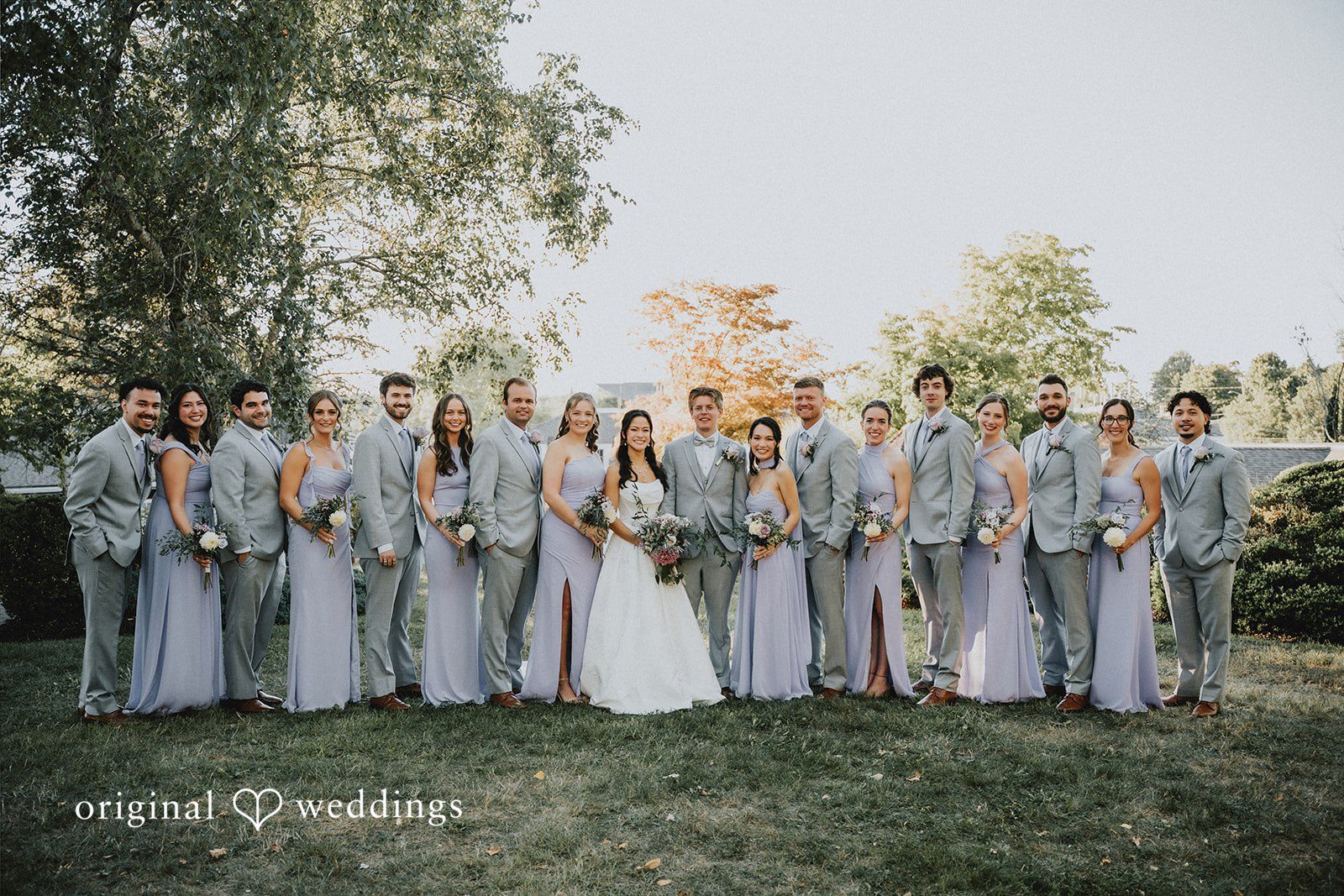 Full bridal party of bridesmaids and groomsmen standing together in a long line.