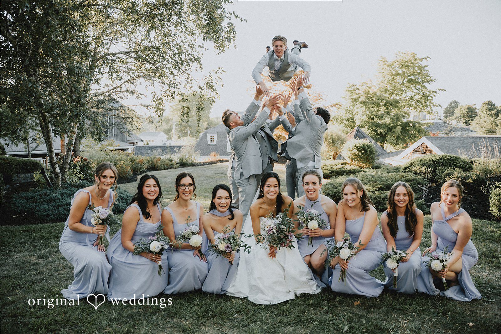 Wedding party gathered together on a hillside for a group photo.