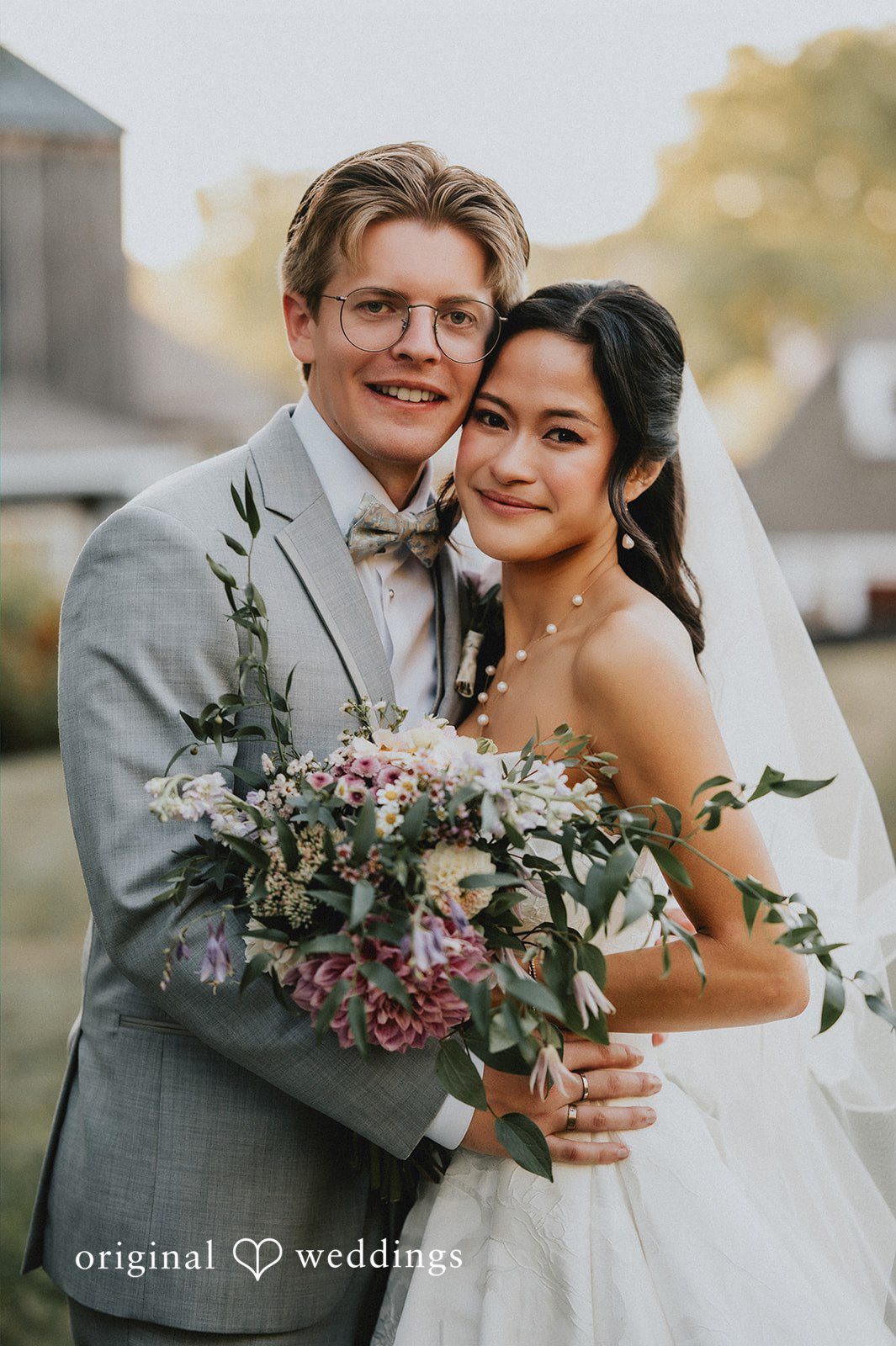 Bride holding a white bouquet next to a groom in a grey suit.