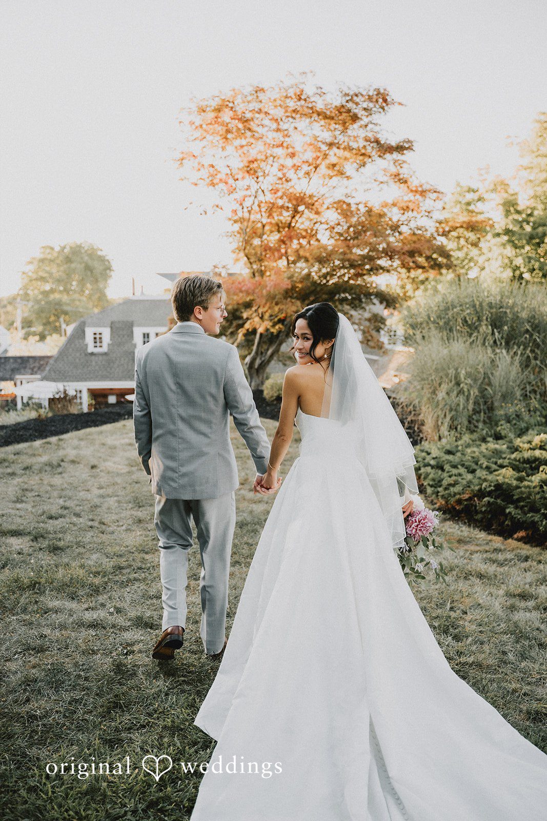Bride and groom walking away together down an open path.