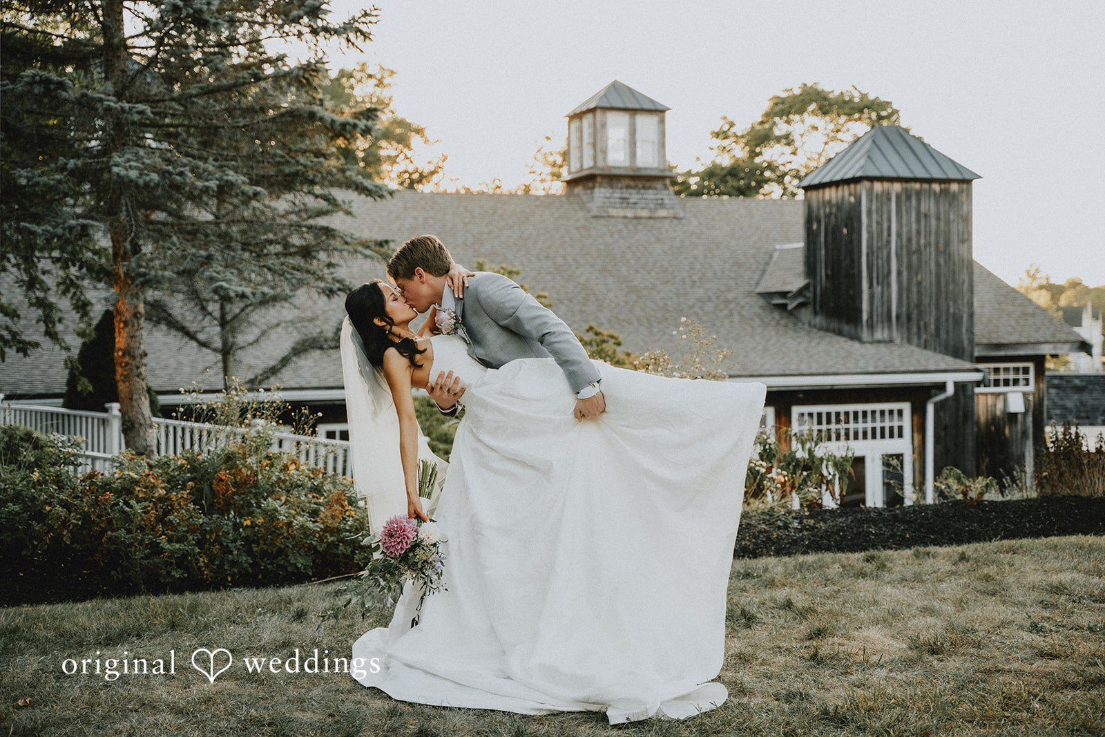 Bride and groom posing together in front of a rustic country house.