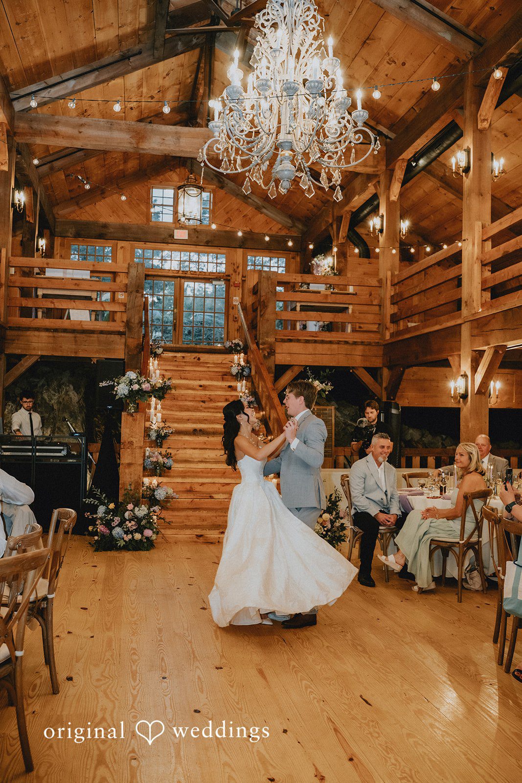 Bride and groom sharing their first dance under a massive crystal chandelier.