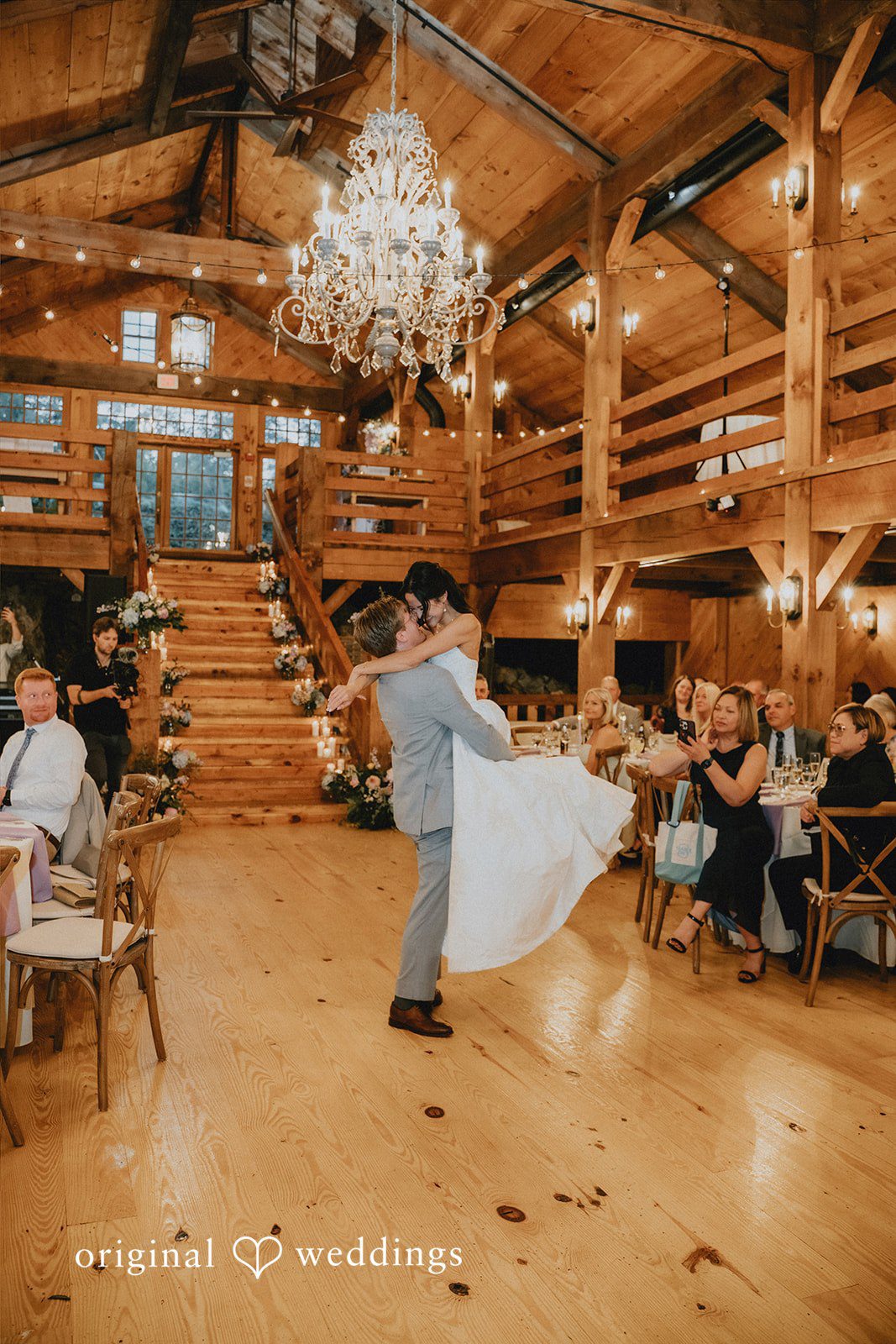 Groom spinning the bride during a dance on a polished wooden floor.