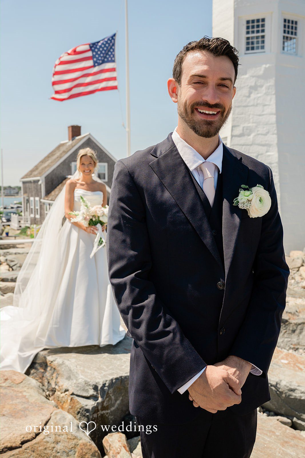 Jessica + Keegan A groom smiling at the camera while standing near a scenic coastal area.