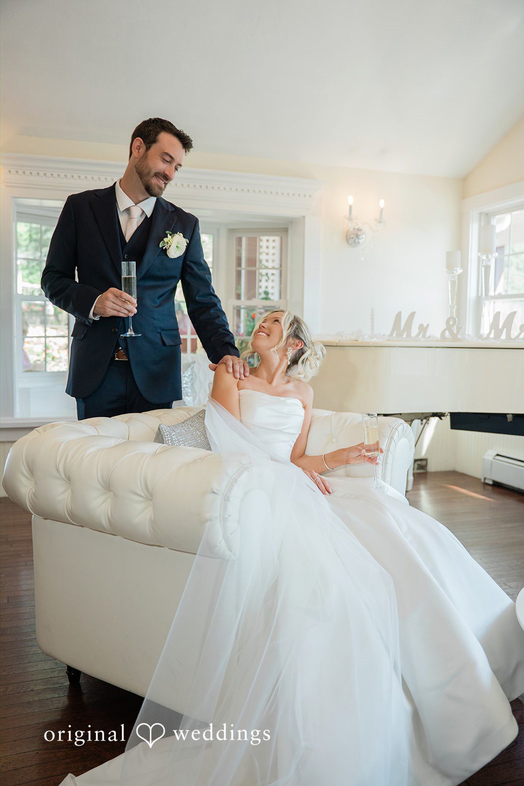 Jessica + Keegan A groom watching his bride walk across a room in her flowing white wedding gown.