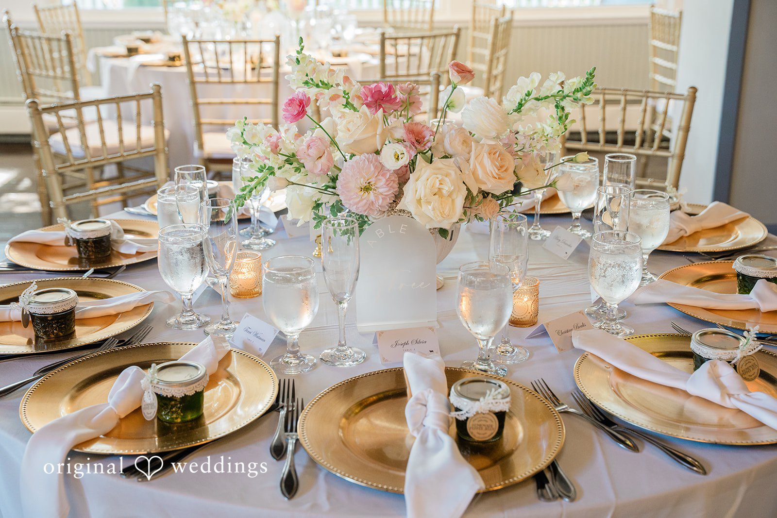 Jessica + Keegan A beautifully set wedding reception table featuring elegant gold chargers, plates, and floral centerpieces.