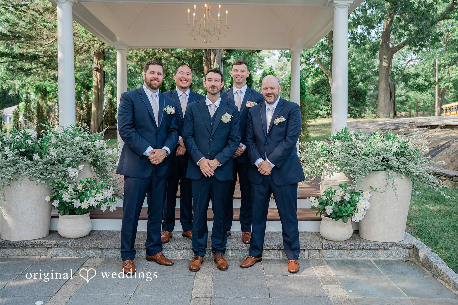 Jessica + Keegan A line of groomsmen standing together in matching navy blue suits before the wedding.