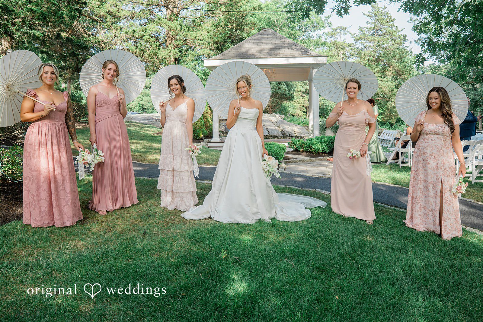 Jessica + Keegan A wedding party featuring bridesmaids in blush dresses and groomsmen in suits standing in a line.