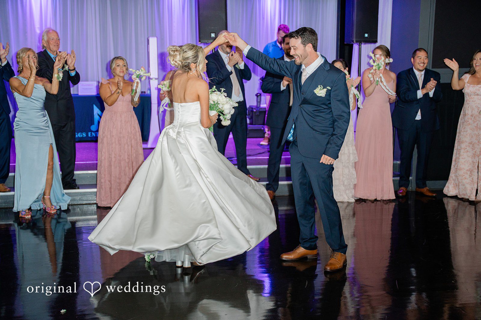 Jessica + Keegan A bride and groom sharing their first dance together on a shiny reception dance floor.