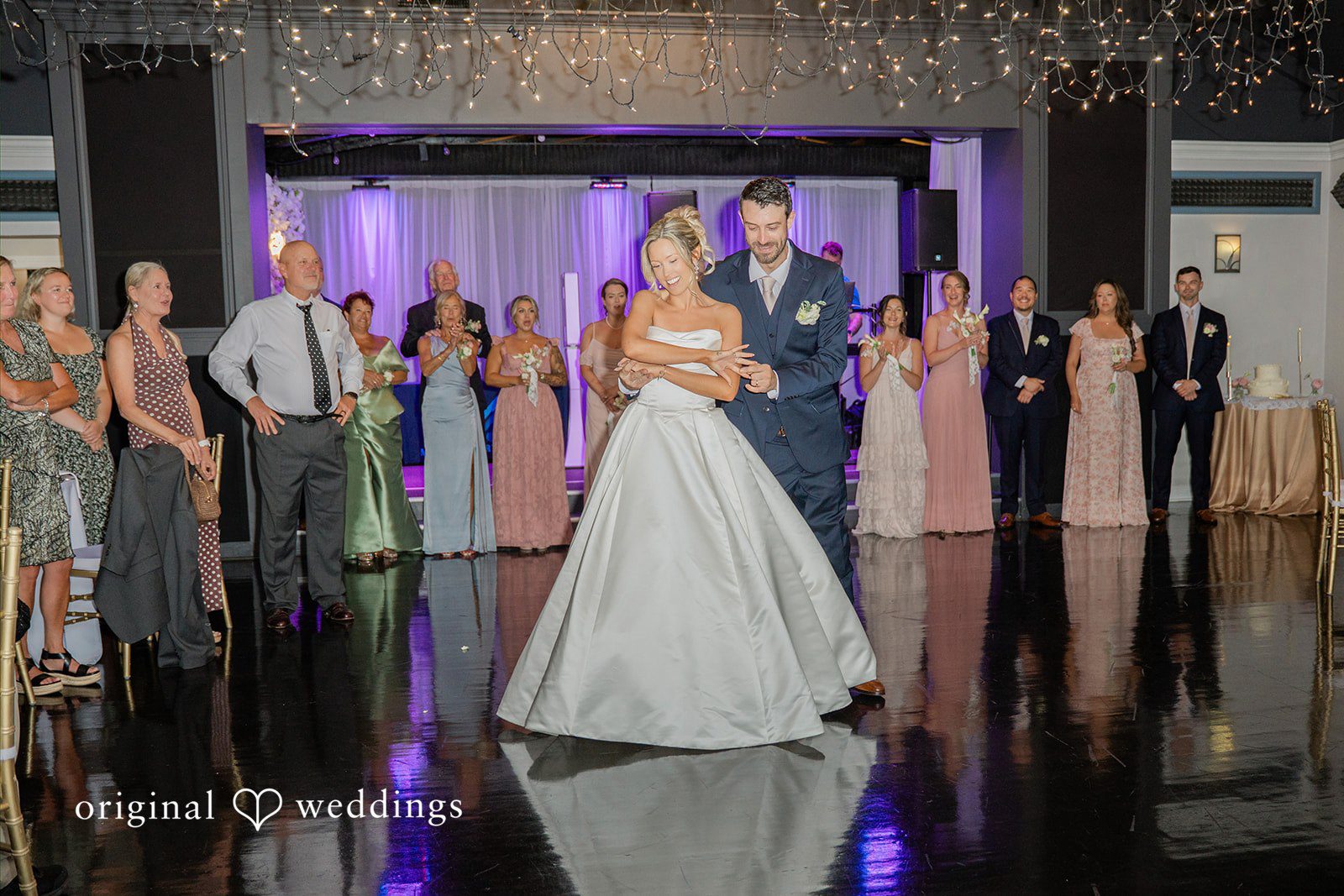 Jessica + Keegan A bride dancing on a reflective floor during a wedding reception with guests watching.