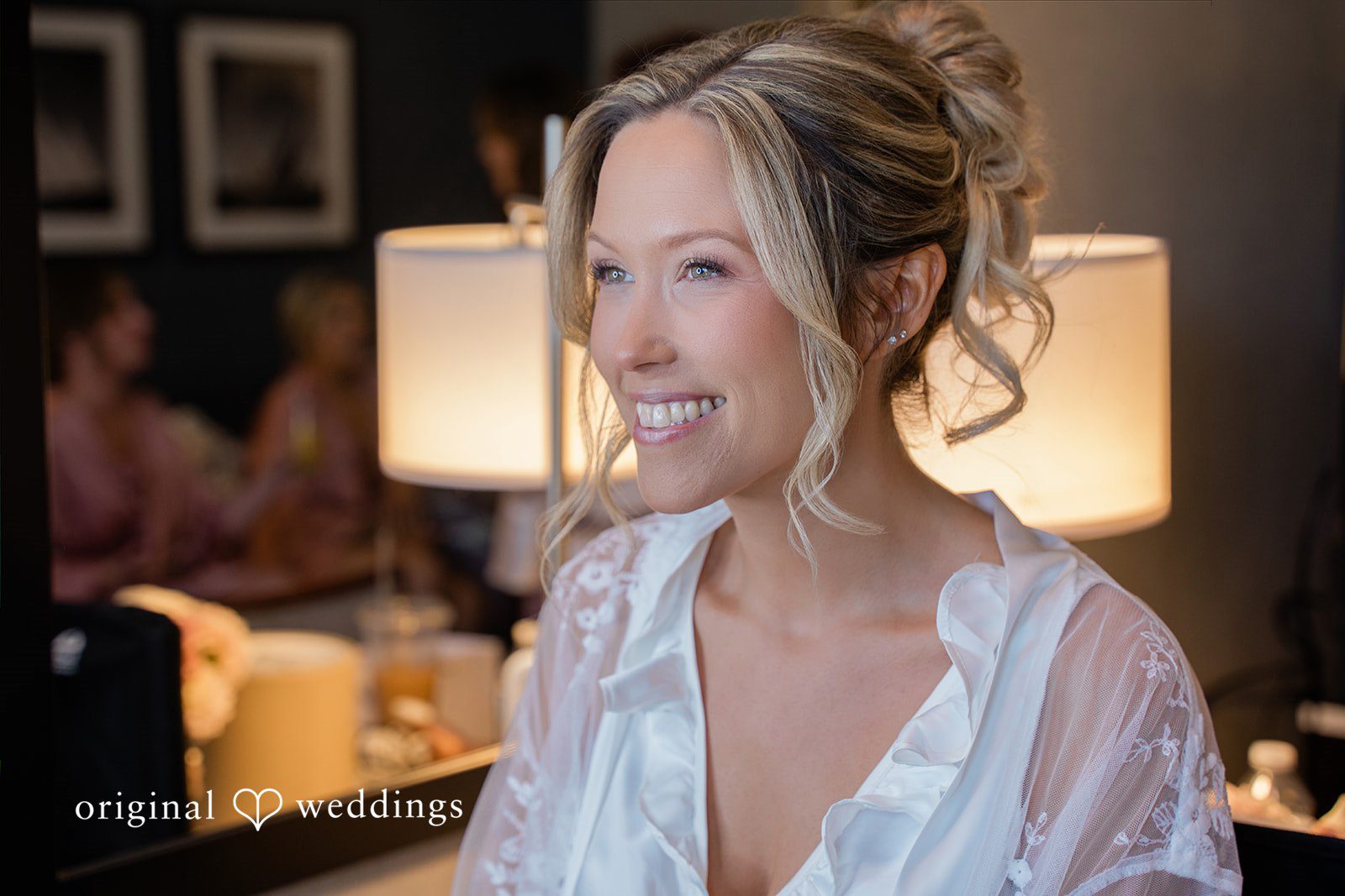 Jessica + Keegan A smiling bride wearing a white lace robe while getting ready for her wedding day.