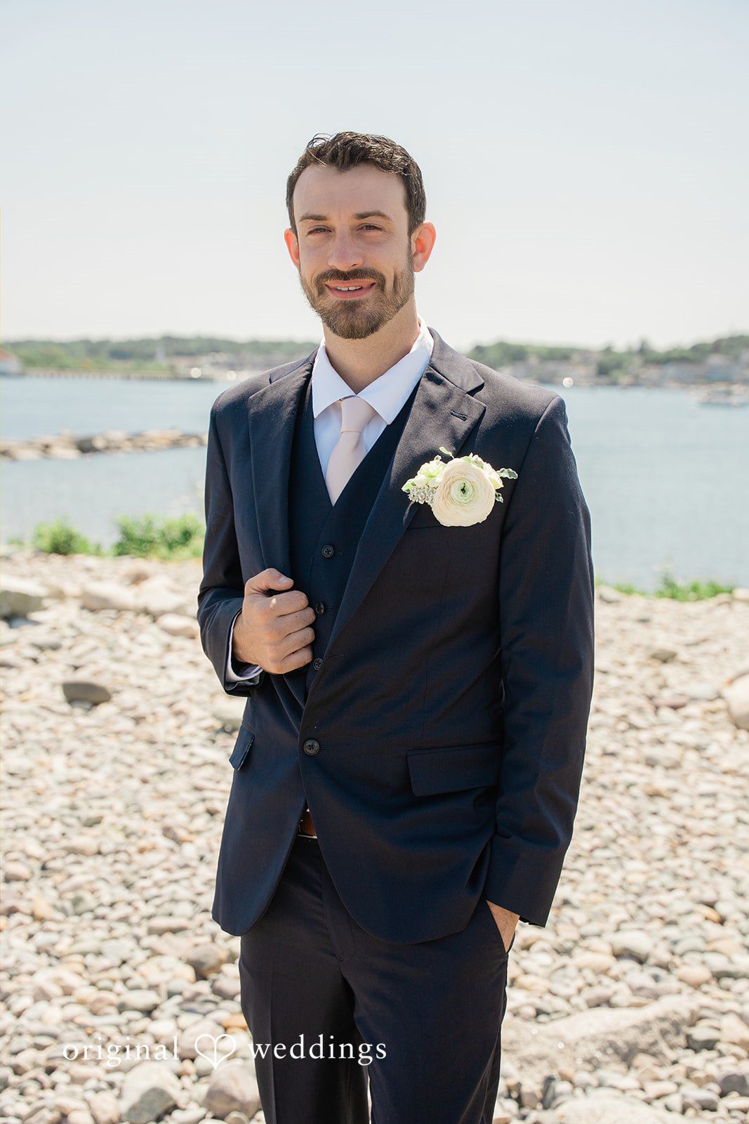 Jessica + Keegan A groom smiling warmly while wearing a classic navy blue suit and tie.