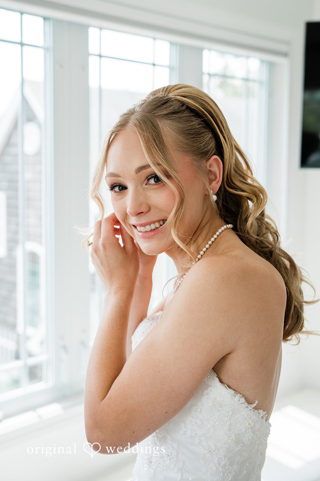 Veronica + Wyatt A smiling bride with wavy blonde hair looking back over her shoulder.