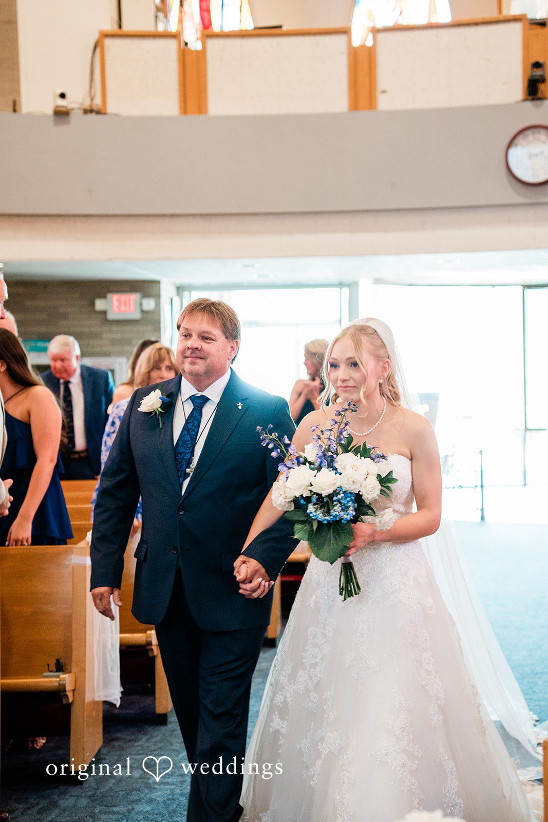 Veronica + Wyatt A bride walking down the church aisle toward the altar.