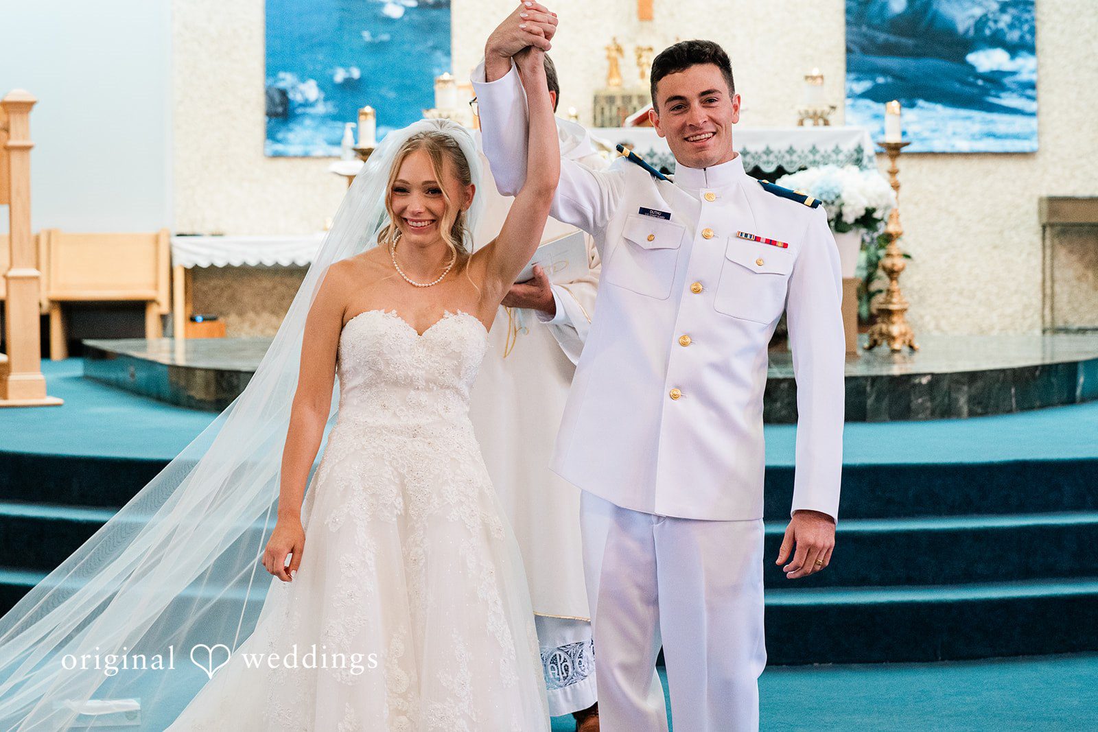 Veronica + Wyatt A bride and groom raising their hands in celebration at the altar.
