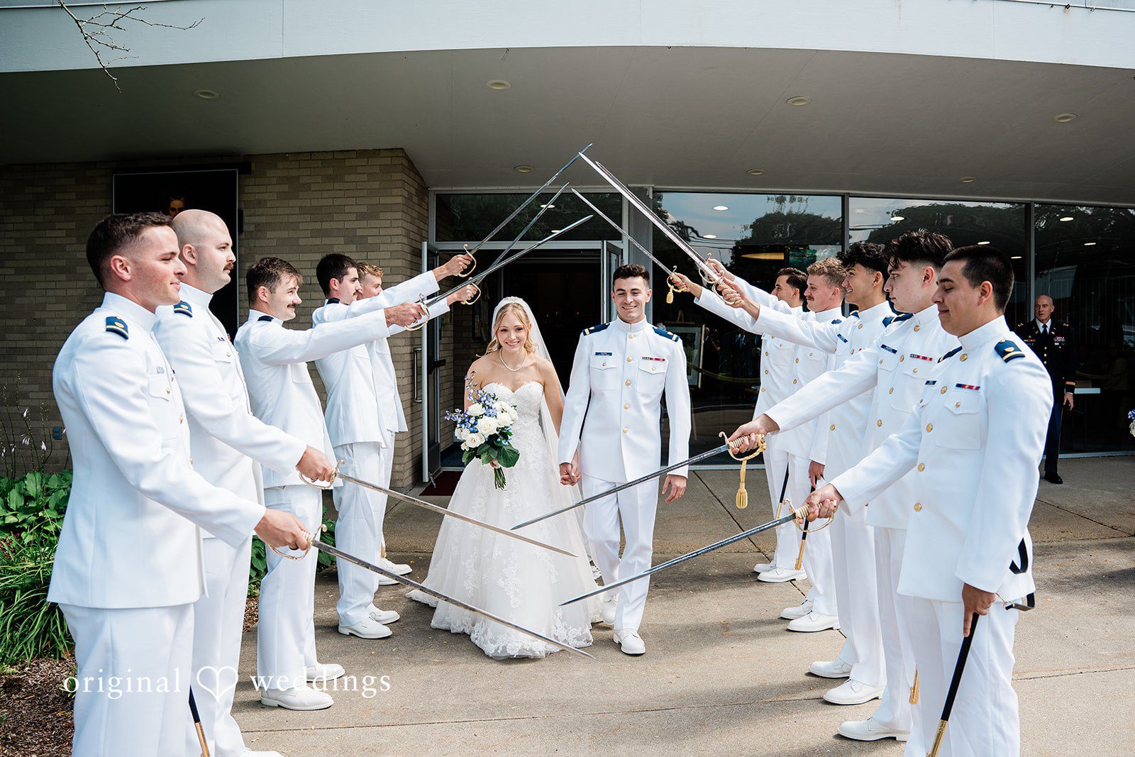 Veronica + Wyatt A wedding party standing together and raising swords for a military arch.