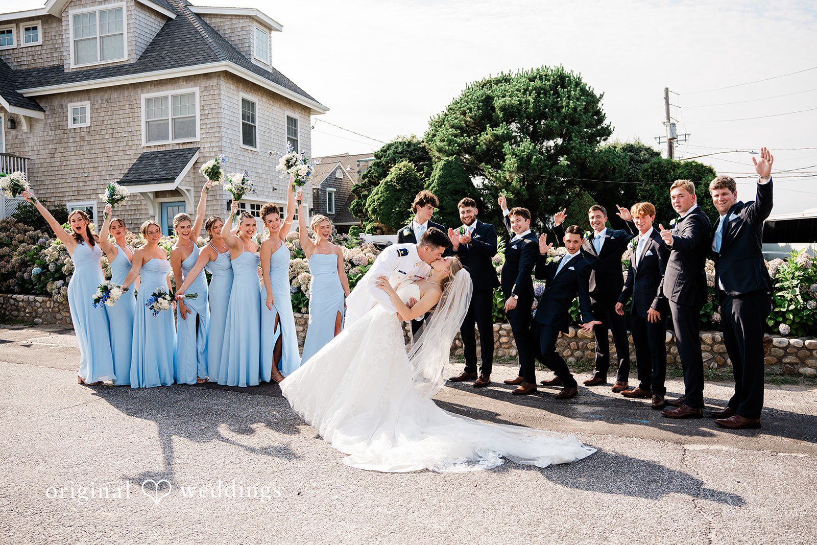 Veronica + Wyatt A wedding party with bridesmaids in light blue and groomsmen in black suits posing together.