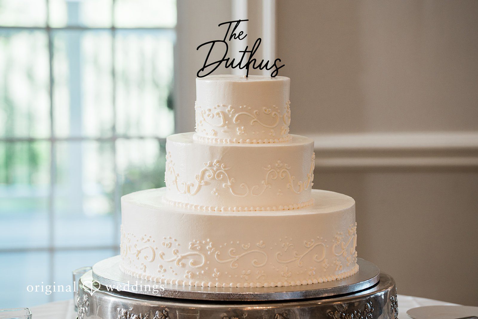 Veronica + Wyatt A multi-tiered white wedding cake decorated with delicate blue flowers.