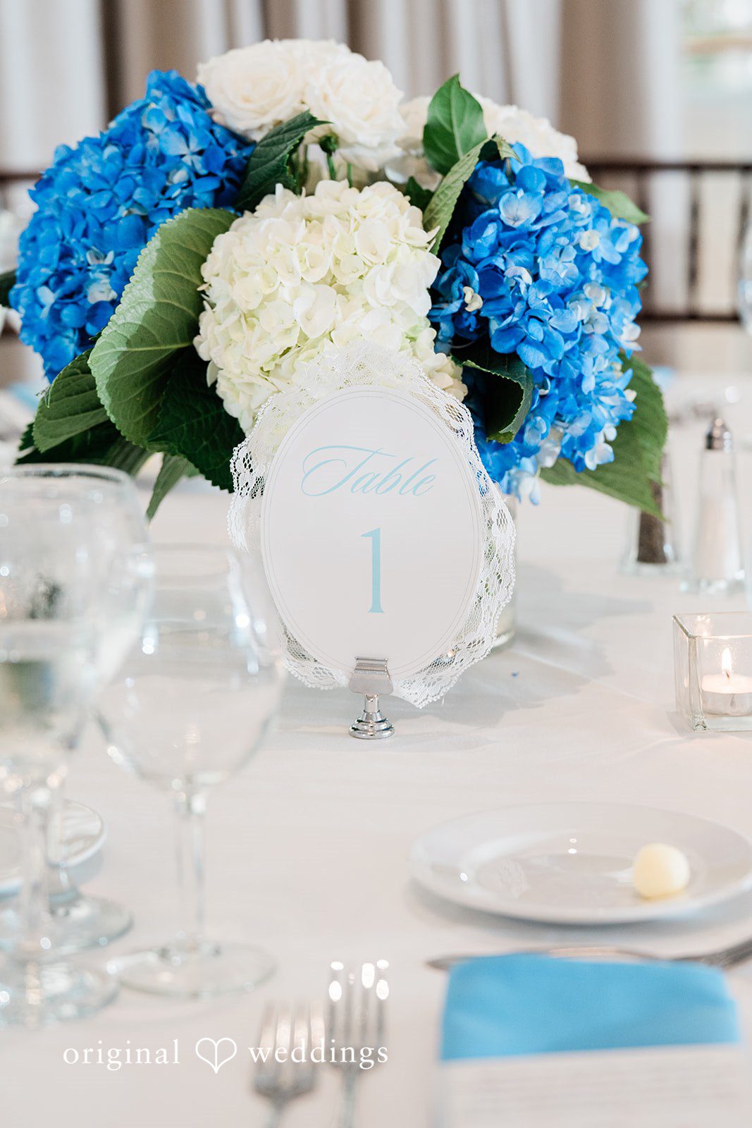 Veronica + Wyatt A close-up of a reception table setting showing a folded white napkin on a plate.