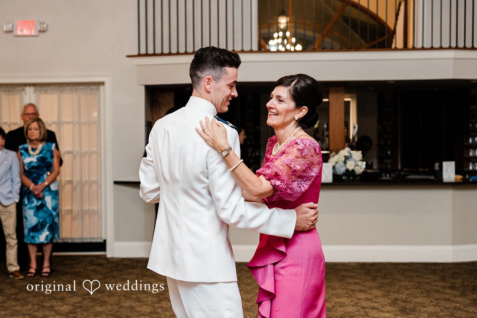 Veronica + Wyatt A groom in a white suit dancing with a woman in a bright pink dress.