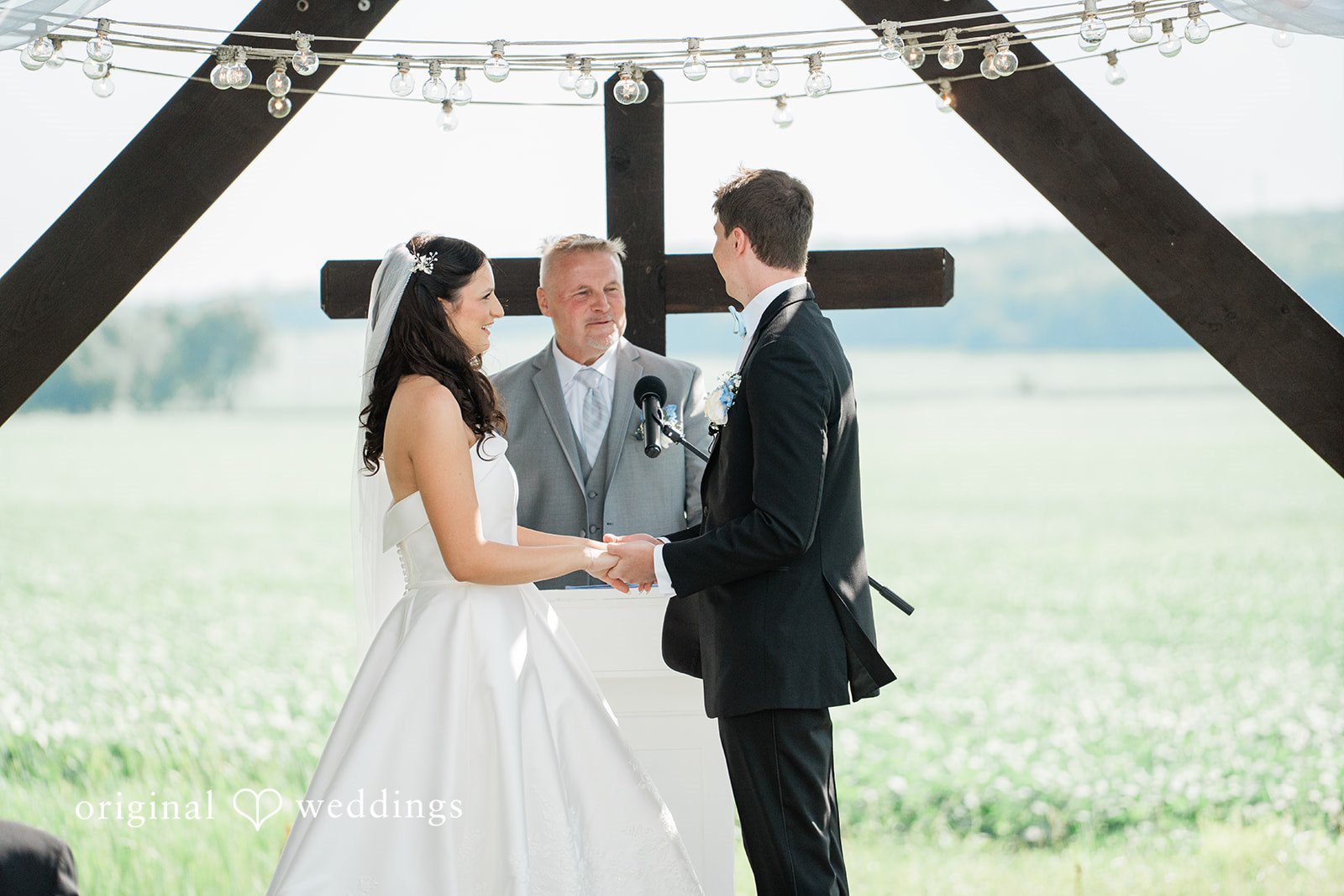 Paige + Stephen A bride and groom holding hands and sharing a moment together during their wedding ceremony.