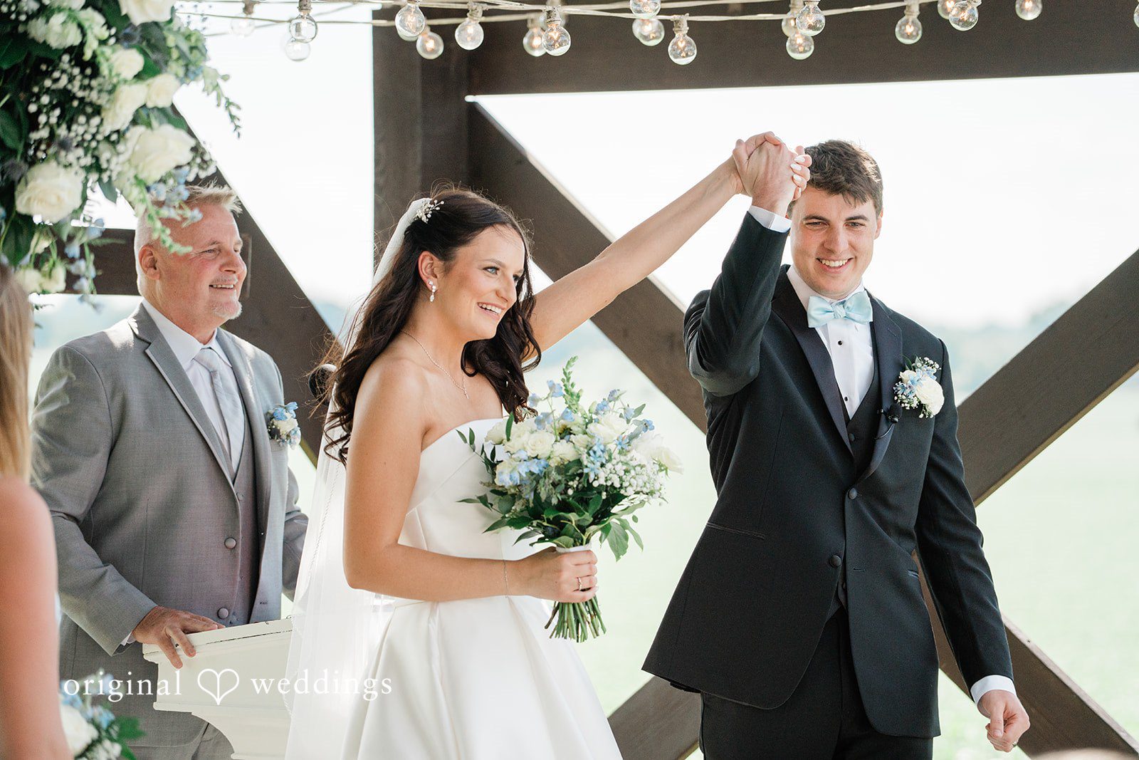Paige + Stephen A bride and groom holding hands and smiling as they walk together down the aisle.